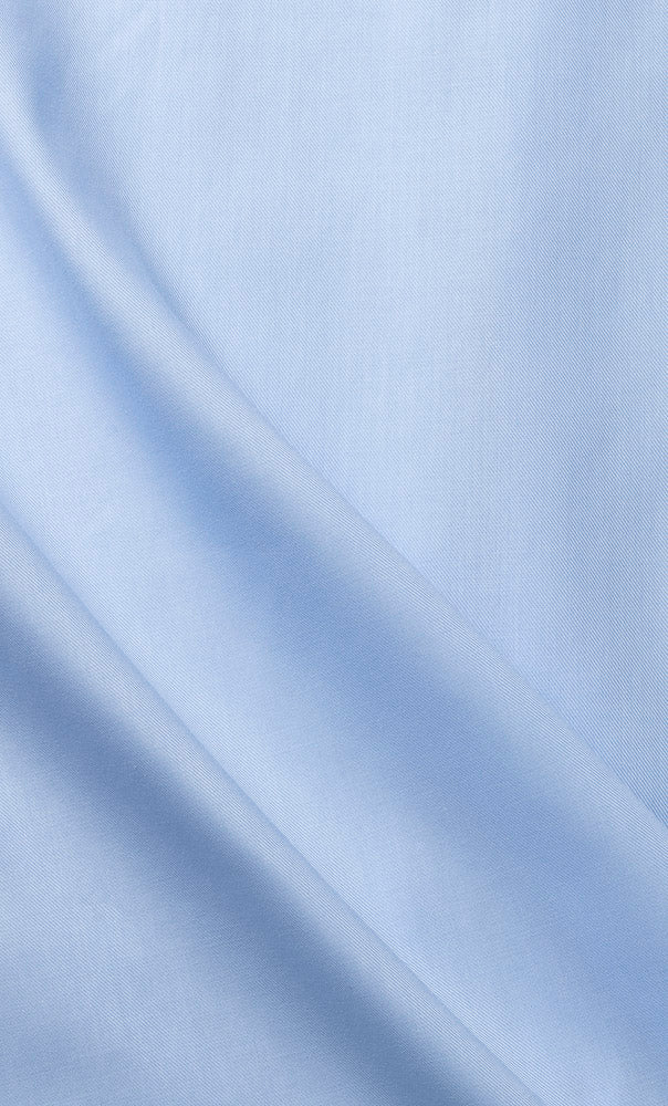 Stoffdetaljer på herreskjorte i lyseblå premium twill med enkel mansjett. Stoffet bølger seg lett, som viser stoffets mykhet og eleganse. Foto