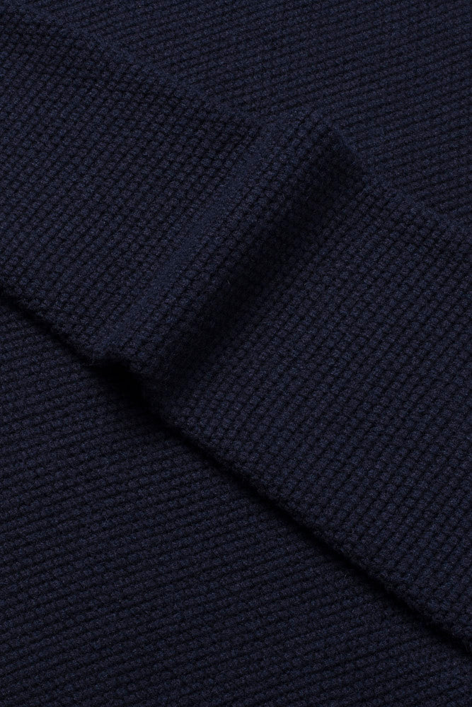Stoffdetaljer av elegant marineblå  genser med hav-zip i perlestrikk. Foto 